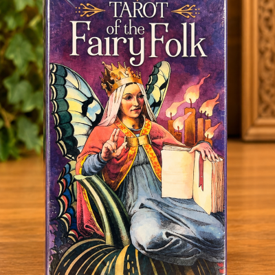 Caixa de tarot com ilustração de fada com asas e coroa segurando um livro.
