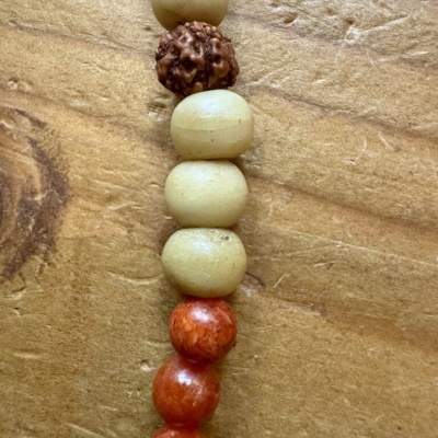 Pulseira ou colar com contas de vários tipos e cores sobre madeira clara