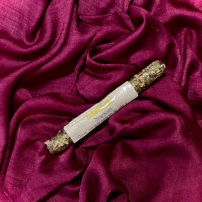 Incenso com embalagem em papel branco sobre tecido rosa escuro brilhante e enrugado