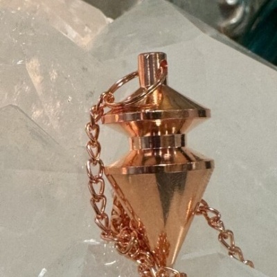 Pêndulo dourado com corrente sobre superfície de cristal