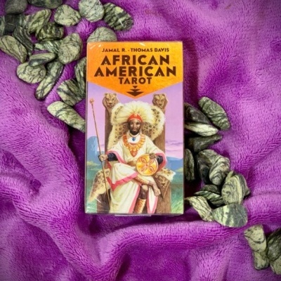 Caixa de baralho de tarot African American Tarot sobre tecido violeta com pedras escuras