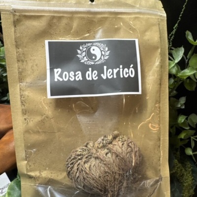 Pacote com planta seca Rosa de Jericó e etiqueta preta com texto e símbolo yin-yang
