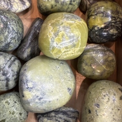 Pedras polidas verdes, amarelas e cinzentas numa caixa de madeira