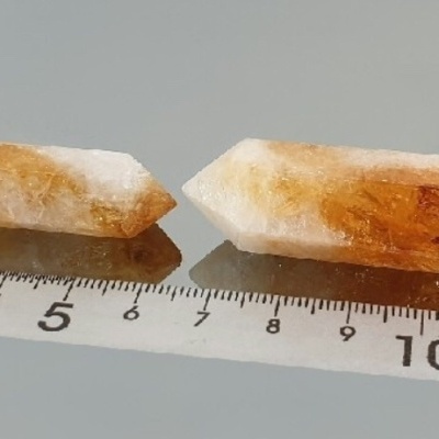 Dois cristais translúcidos âmbar e branco com régua em superfície espelhada