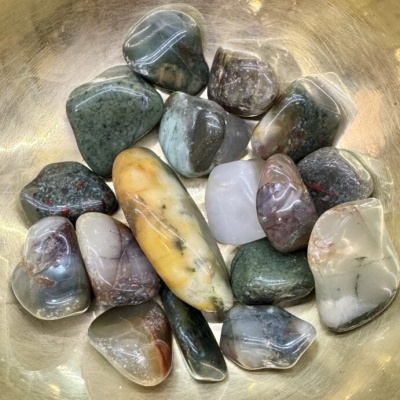 Conjunto de pedras polidas de várias cores numa superfície dourada.