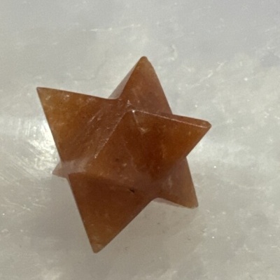 Estrela de pedra translúcida cor de ferrugem sobre superfície branca brilhante