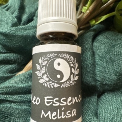 Frasco de óleo essencial Melisa com símbolo yin-yang e flores sobre tecido verde