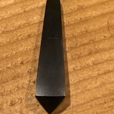 Colar pendente pêndulo preto sobre superfície de madeira clara