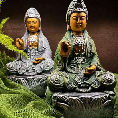 Esculturas decorativas em verde e cinza com detalhes laranja sentadas sobre bases ornamentadas.