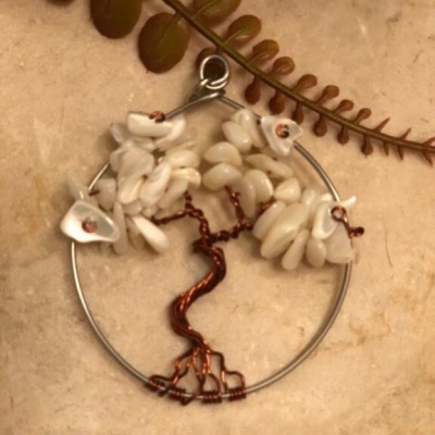 Pendente artesanal árvore da vida com pedras brancas e arame cobre em fundo bege