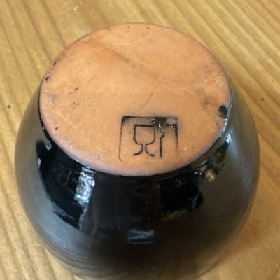 Recipiente de cerâmica vidrado preto com base de terracota e símbolo copo e talheres