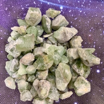 Pedaços brutos de pedras verdes sobre fundo roxo estrelado