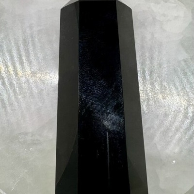 Cristal preto facetado sobre base translúcida esbranquiçada