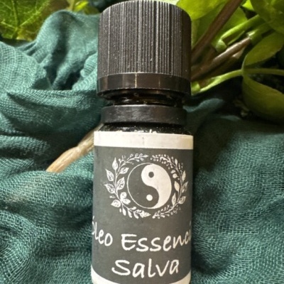 Frasco de óleo essencial com rótulo preto e símbolo yin-yang sobre tecido verde