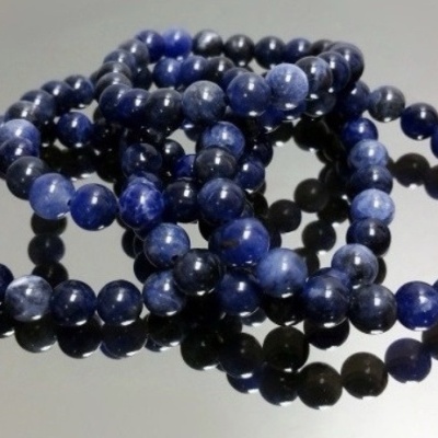 Pulseiras de contas azuis esféricas sobre superfície preta refletora