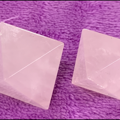 Dois cristais rosa em forma de pirâmide sobre tecido roxo