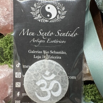 Colar esotérico com pendente branco translúcido e símbolo ॐ em saco plástico com cartão da loja Meu Sexto Sentido