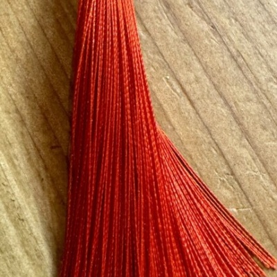 tassel vermelho de seda sobre madeira clara
