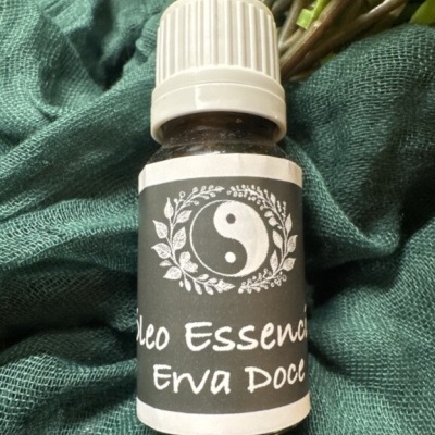 Frasco pequeno de óleo essencial de Erva Doce com rótulo preto e símbolo yin-yang sobre tecido verde.