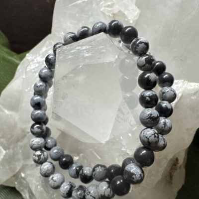 Pulseira de bolas pretas e brancas sobre cristal translúcido com fundo verde