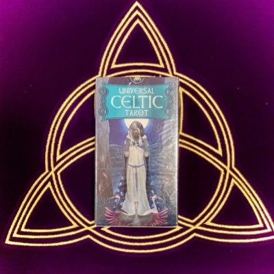 Baralho de tarot Universal Celtic Tarot com figura feminina, padrão celta amarelo sobre fundo roxo.