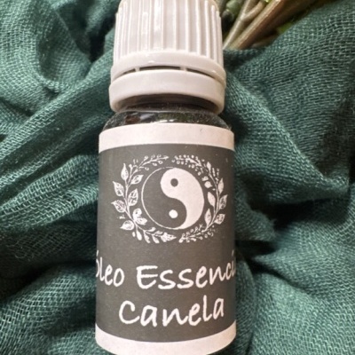 Frasco de óleo essencial de canela com etiqueta preta e símbolo yin-yang sobre tecido verde
