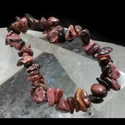 Pulseira de pedras naturais irregulares rosa, preto e castanho sobre superfície translúcida