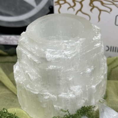 Vela de selenite branca translúcida com musgo verde e cristais brancos