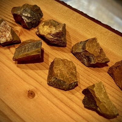 Pedaços de pedra castanhos e cinzentos sobre mesa de madeira clara