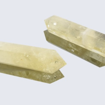 Dois cristais amarelo transparente alongados com pontas facetadas sobre fundo branco