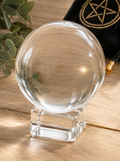 Esfera de cristal transparente sobre base cúbica em cristal sobre mesa de madeira clara