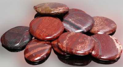 Pedras polidas redondas e achatadas em tons vermelhos e castanhos