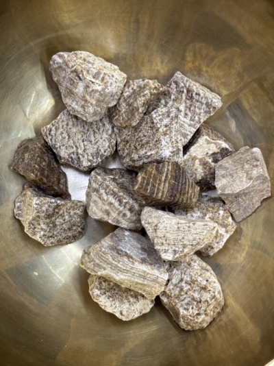 Pedras castanhas estriadas em bacia metálica dourada