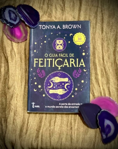 Livro O Guia Fácil de Feitiçaria de Tonya A. Brown com pedras de ágata coloridas sobre tecido dourado.