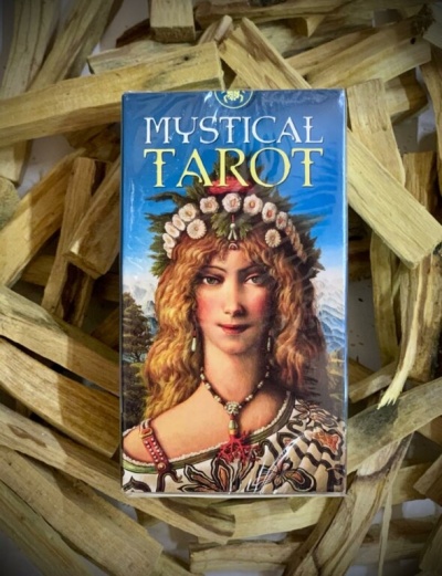 Baralho Mystical Tarot com imagem de mulher loira com coroa de flores em fundo de madeira clara