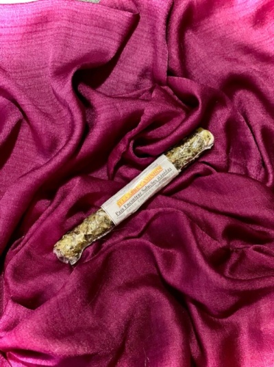 Incenso enrolado com etiqueta branca sobre tecido cor de vinho