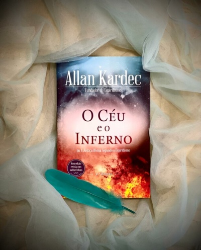 Livro O Céu e o Inferno de Allan Kardec sobre tecido transparente bege com pena azul