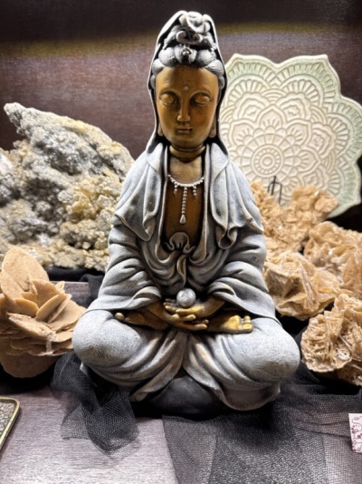 Estátua de Buda meditando em cinzento e dourado com minerais ao redor