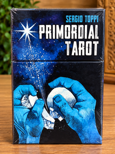 Caixa de tarot Primordial Tarot com ilustração de mãos azuis segurando ovo partido