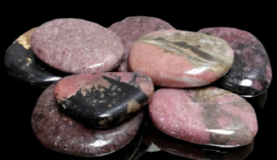 Pedras polidas cor-de-rosa com manchas pretas e cinzentas sobre fundo preto