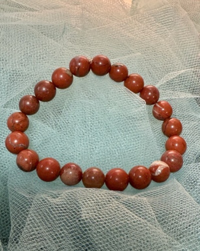 Pulseira com contas vermelhas e castanhas em tecido branco transparente