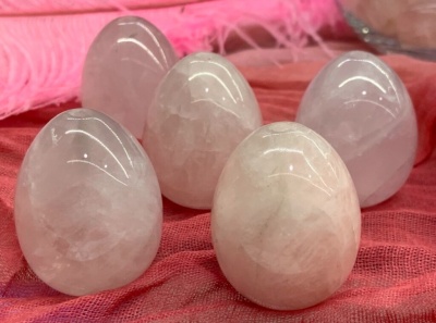 Cinco ovos de quartzo rosa polidos sobre tecido vermelho