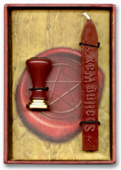 Conjunto para lacre com selo e vela vermelha em fundo decorativo com pentagrama
