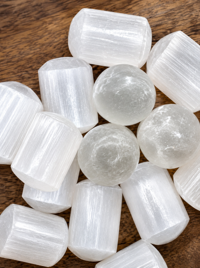 Pedras de selenite brancas translúcidas cilíndricas e esféricas sobre madeira castanha