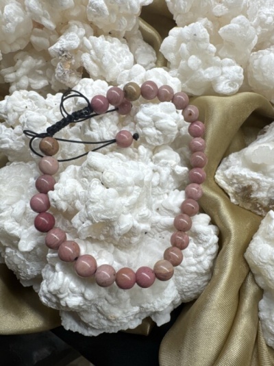 Pulseira rosa e bege sobre pedras brancas e tecido dourado