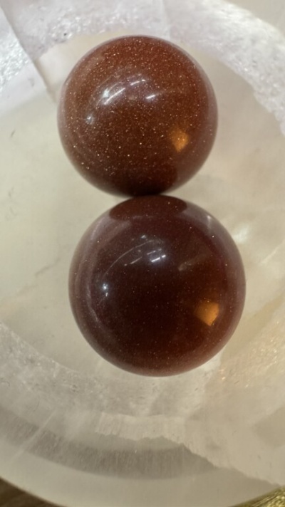 Duas esferas castanhas brilhantes num recipiente translúcido