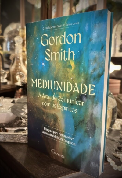 Livro Mediunidade de Gordon Smith com capa azul e verde sobre superfície de madeira