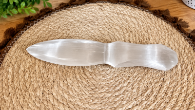 Espátula em selenite branca translúcida sobre tapete trançado