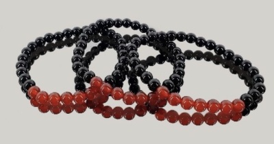 Pulseiras de contas pretas com secção vermelha sobre fundo cinza claro