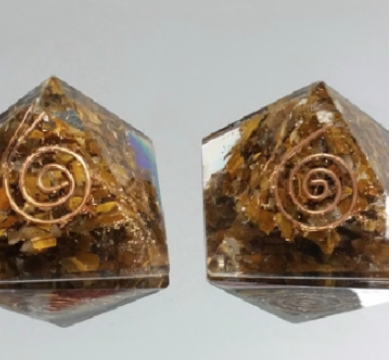 Dois objetos piramidais de resina translúcida com inclusões douradas e espiral de cobre